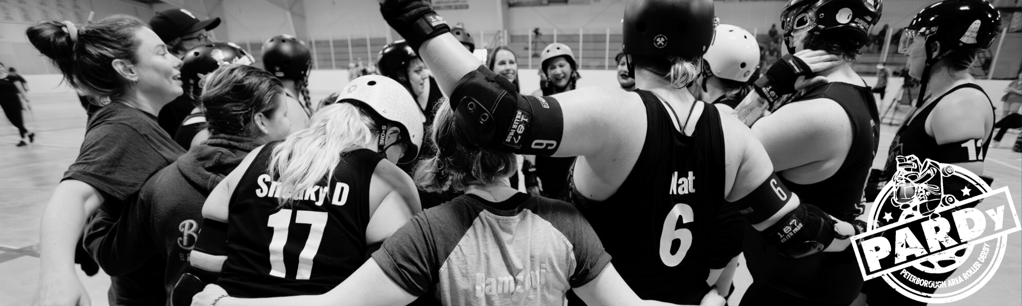 black and white rear view of skaters with arms around each other's shoulders in huddle